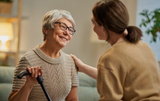 Happy patient and caregiver spending time together. Senior woman holding cane.